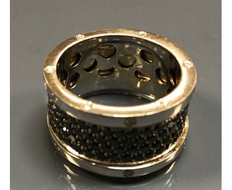 An 18 carat gold band ring, the outer bands set with 24 small diamonds, the revolving centre set with multiple black diamonds
