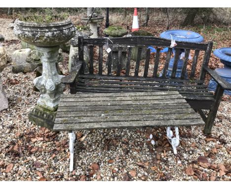 A slatted wooden garden bench seat and a slatted wooden table on painted metal scroll supports, together with a natural stone