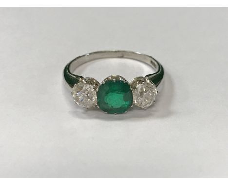 An 18 carat white gold set dress ring, set with emerald, approx 1.25 carats, flanked by two diamonds, approx 0.5 carat each, 