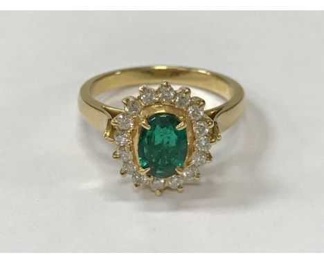 An 18 carat gold dress ring set with oval cut emerald, approx 0.65 carat, within a band of 16 small diamonds, 5 g, size O