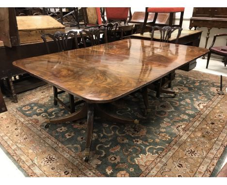 A late George III mahogany twin pillar dining table with two rounded rectangular end sections and two leaves raised on quadru