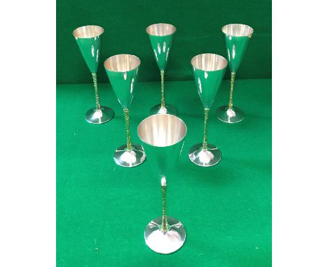 A set of six Stuart Devlin flutes of conical form, raised on silver gilt bark effect stems to splayed circular foot (London 1