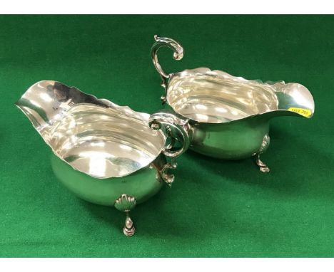 A pair of Edwardian silver sauceboats of inverted helmet form, raised on foliate decorated hoof feet (by Hamilton &amp; Inche