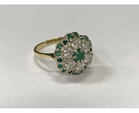 An 18 carat gold emerald and diamond cluster ring, size O