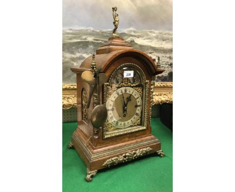 An early 20th century oak cased mantle clock with gilt brass embellishments, the 8 day musical movement with brass arch dial 