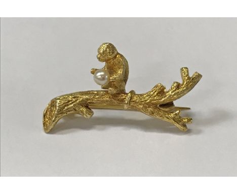 A 9 carat gold bar brooch as a monkey upon a branch holding a seed pearl, 4.1 g