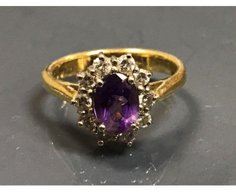 An 18 carat gold ladies dress ring set with central amethyst, approx 0.75 carat within a band of ten small diamonds, size L