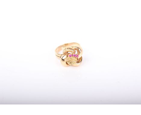 A Continental yellow metal and small ruby three stone leaf and entwined scroll ring, the flat section shank stamped ‘750’, si