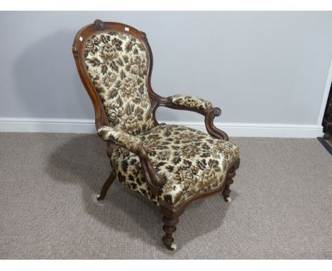 A late Victorian carved walnut open Armchair, with floral upholstery and ceramic casters, 25in (63.5cm) wide x 32in (81cm) de