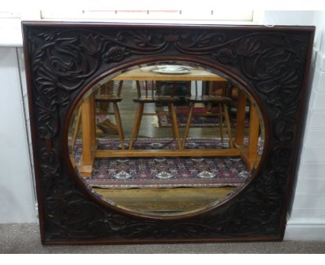 A large Arts and Crafts style oak framed Mirror, with naturalistic foliate moulded border in relief, enclosing the ovular bev