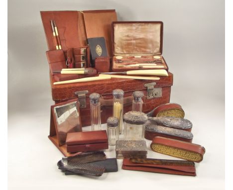 DRESSING CASE.A crocodile dressing case, well filled with four silver mounted brushes & six silver mounted jars & bottles. Th