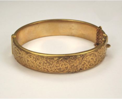 GOLD BANGLE.A 9ct. gold engraved hinged bangle (wax filled). 22.8g.  