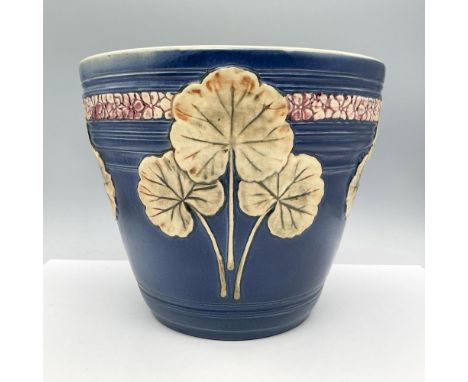 Features a rich blue background, decorated with a raised relief design of green geranium leaves, which are realistically deta