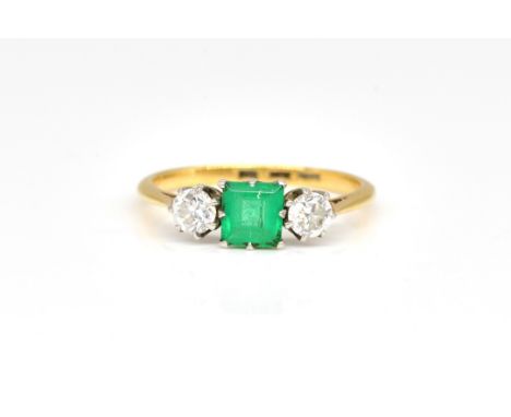 A GOLD, EMERALD AND DIAMOND THREE STONE RINGClaw set with the square step cut emerald at the centre, between two circular cut