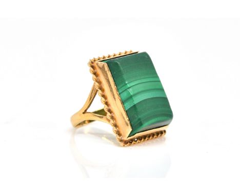 A GOLD AND MALACHITE SINGLE STONE RINGMounted with a rectangular malachite within a twisted wirework surround, detailed 18 K,