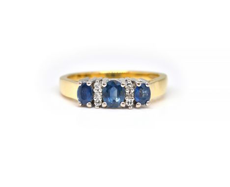 AN 18CT GOLD, SAPPHIRE AND DIAMOND RINGClaw set with three oval cut sapphires and with two rows of three small circular cut d