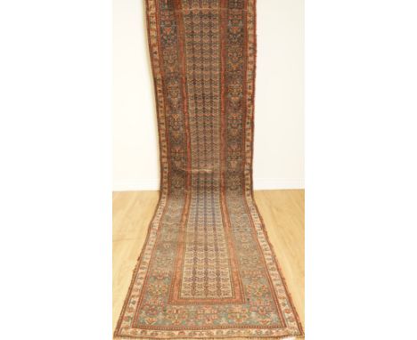 A NORTH WEST PERSIAN RUNNERThe ivory field with rows of cross motifs; an indigo floral border; circa 1900s; 450 x 106cmCondit