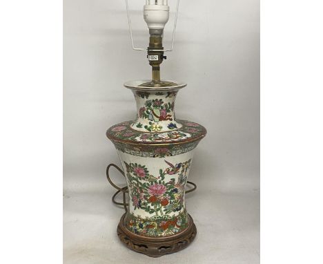 A LARGE CHINESE PORCELAIN TABLE LAMP DECORATED WITH FLOWERS, FOILAGE AND PICTURESQUE CHARACTERS ON A WOODEN STAND