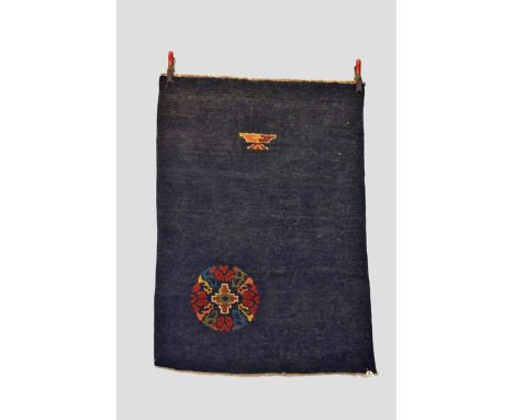 Two Tibetan rugs, mid-20th century, the first plain dark blue with floral roundel in lower left corner; small foliate motif a