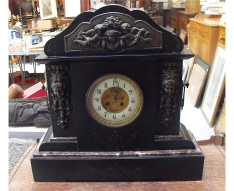 A Victorian black slate architectural mantle clock the enamel dial with Arabic numerals and open escapement and figural mount
