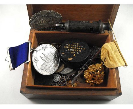 A New York chauffeur numbered registration badge, a 1947 Butlins enamel badge, badges and other items in a walnut box 