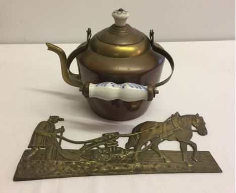 A vintage brass kettle with ceramic handle and finial together with a brass plaque of a farmer and plough.