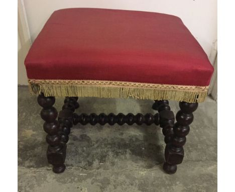 A large square bobbin leg stool with red upholstery.