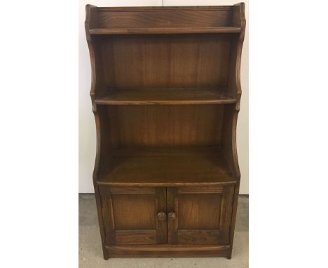 A small Ercol waterfall book case with 2 door cupboard. Base 110cm high.