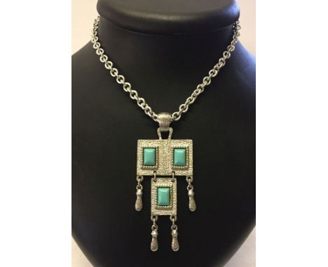 A vintage Sarah Coventry silvertone pendant on a 30" chain with decorative turquoise blue panels. Pendant measures approx 9cm