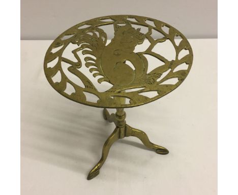 A brass trivet on tripod stand depicting a squirrel.