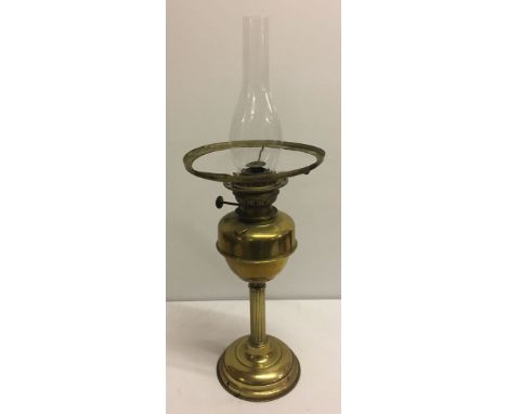 A large brass oil lamp with fluted stem and glass chimney (shade missing).