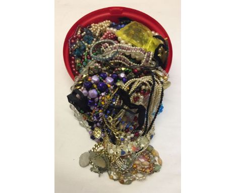 A round tub with a large amount of modern and vintage costume jewellery including faux pearl, glass beads etc.