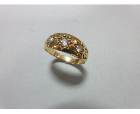 A Victorian diamond three stone ring, the three old European cut diamonds claw set in star shaped recesses to foliate heart c