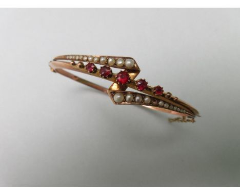 A seed pearl and red spinel hinged bangle, the hollow triangular section bangle set to the front with a graduated line of rou