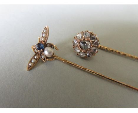 A diamond stick pin together with a gemset insect stick pin, the first a cluster of nine rose cut diamonds around a larger si