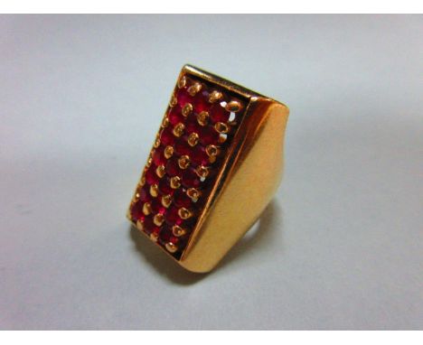 A rectangular ruby dress ring, the twenty-one round cut rubies set in a regular panel with solid curved surround tapering int