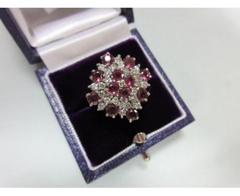 A ruby and diamond cluster ring in 18ct white gold, designed as a densely set diaper with a quatrefoil of rubies in the centr