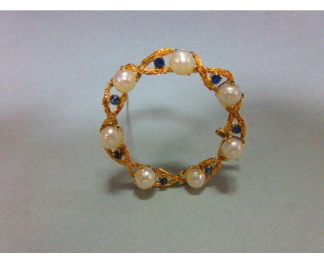 A pearl and sapphire hoop brooch, the pierced hoop formed by two twining and textured stems set at intervals alternately with