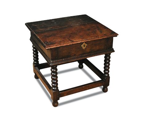 A 17th century oak box stool, hinged top, on turned stretched legs, 46cm (18in) high x 56cm (22in) wide x 45cm (17.5in) deep 
