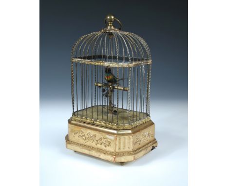 A late 19th or early 20th century singing bird automaton, the small feather bird sits upon a brass perch within a gilt brass 