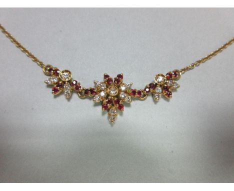 An 18ct gold ruby and diamond necklace,   set to the front with a graduated trio of flower motifs set throughout with round b