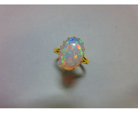 A single stone opal ring, the oval cabochon opal displaying a vivid rainbow play of colour, claw set to a raised coronet gall