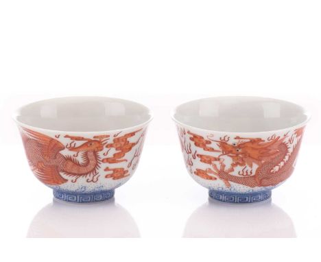 A pair of Chinese porcelain bowls, painted in iron red, one with a dragon the other with a fenghuang, each chasing a flaming 