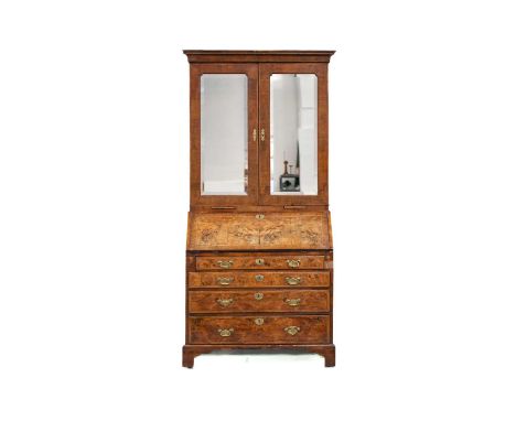 A George I walnut bureau bookcase the upper section with cross-grain cornice above a pair of mirror panel doors with adjustab