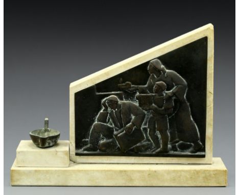 A marble and brass stand for a Holocaust memorial candle. With a relief depicting a Jewish refugee, behind him - a mother and