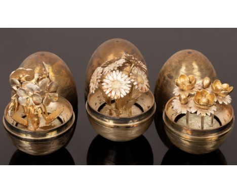 Nicholas Plummer, three silver and silver gilt surprise eggs, each with textured exterior and interior with clump of flowers: