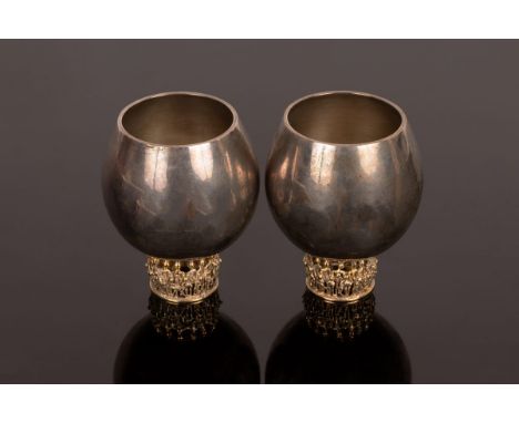 Stuart Devlin (1931-2018), a pair of silver whisky tots, each with plain bowl gilt to the interior on a cast silver-gilt cary