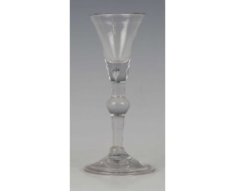 A balustroid gin or cordial glass, circa 1730-40, the rounded funnel bowl with teared solid base, raised on a centrally knopp