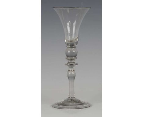A Newcastle type light baluster wine glass, circa 1730-40, the bell bowl above a ball knop between two collars, over a bladed