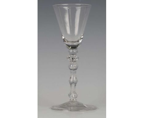 A Newcastle type light baluster wine glass, circa 1730, the pointed rounded funnel bowl above two knops, the centrally knoppe